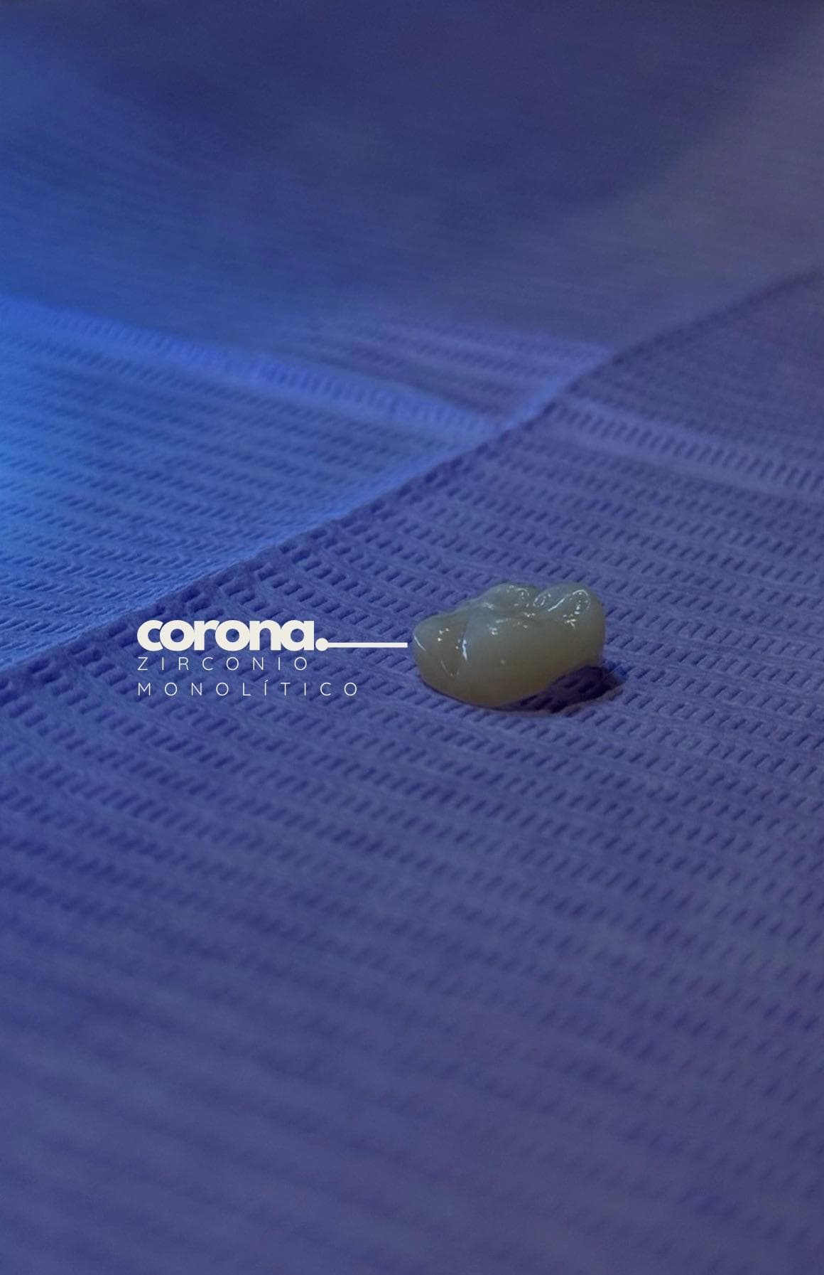 Corona de zirconio monolítico sobre el campo azul del consultorio, con el rótulo del consultorio